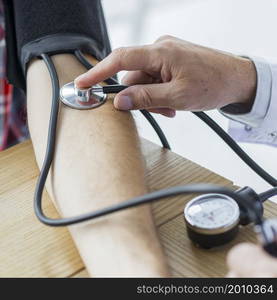 crop hand with stethoscope measuring blood pressure