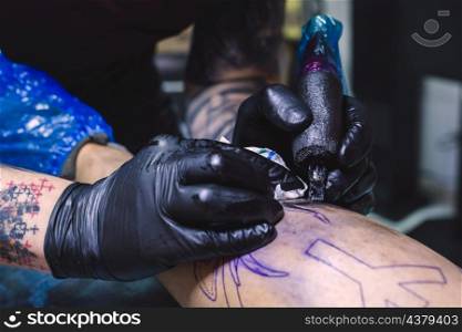 crop hands doing tattoo with machine