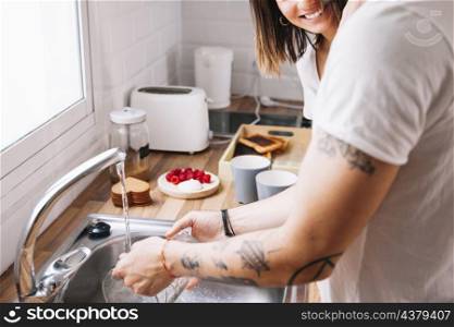 crop man washing dishes near woman