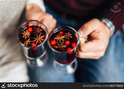 Crop people clinking with glasses full of mulled wine withs spices. . Crop people holding hot punch