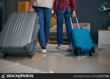 Crop shot of couple walking with suitcases. Home living room interior. Tourism and vacation concept. Crop shot of couple walking with suitcases