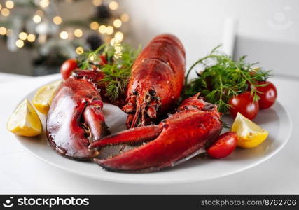 Crop shot of freshly cooked red lobster with vegetables on a plate and white table. Christmas light on a background. Holidays food concept. Freshly cooked lobster with vegetables on a plate