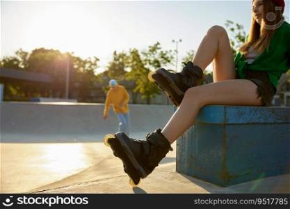 Crop shot of relaxed woman sitting on rollerdrom. Teenager female rollerskater rest after free riding activity. Crop shot of relaxed woman sitting on rollerdrom