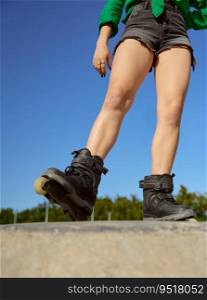 Crop view of teenager girl on roller skates posing for camera over blue sky. Healthy lifestyle and sports activity. Crop view of teenager girl on roller skates