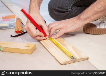 Cropped hand of a carpenter taking measurement of a wooden plank