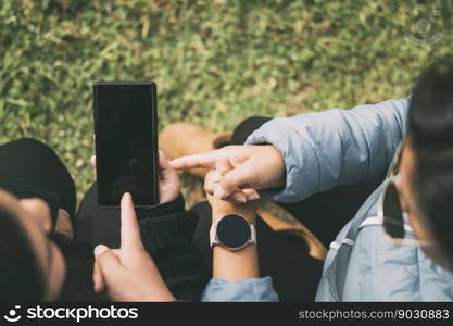 Cropped hands of a woman with a smart watch, pointing to a smartphone, concept of technology, social networking, with two people indicating something on the smartphone.. Cut out hands of a woman with a smart watch, pointing to a smartphone, technology concept, social networks, etc.