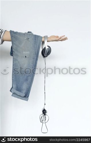 Cropped Image Of a Woman Holding Jeans And Headphones Over White Background