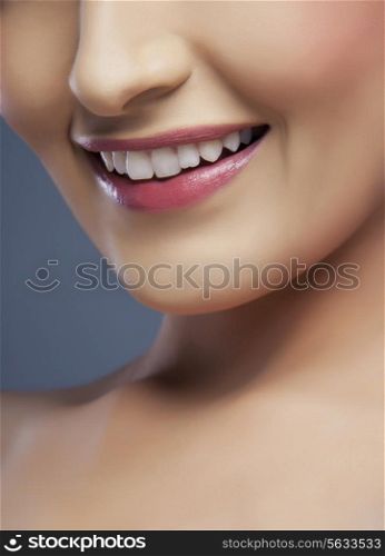 Cropped image of a young woman&rsquo;s beautiful smile over colored background