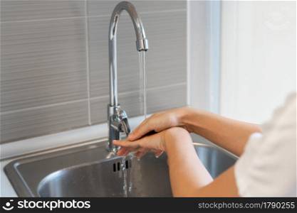 Cropped image of Asian woman washing hands in sink before cooking at home kitchen.