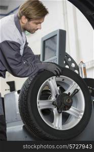 Cropped image of automobile mechanic repairing car&rsquo;s wheel in workshop