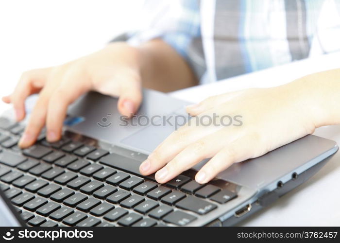 Cropped image of boy&#39;s schoolboy&#39;s hand typing on laptop keyboard