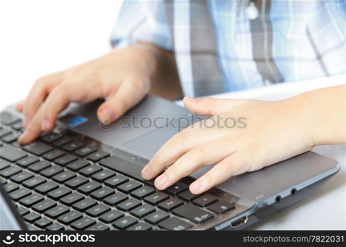 Cropped image of boy&#39;s schoolboy&#39;s hand typing on laptop keyboard