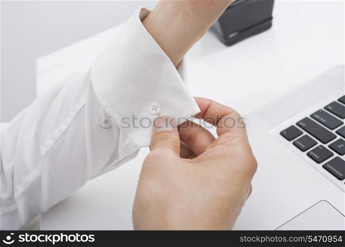 Cropped image of businessman buttoning his cuff in office