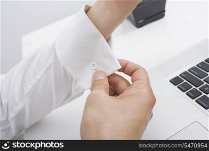 Cropped image of businessman buttoning his cuff in office