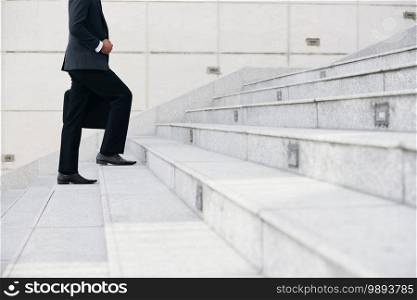 Cropped image of businessman walking up the stairs. Career ladder