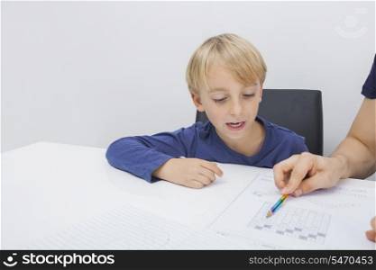 Cropped image of father assisting boy in studies