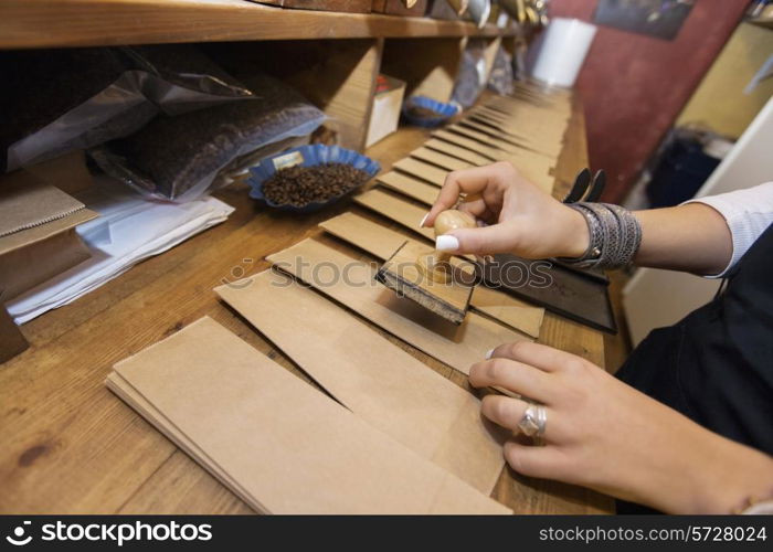 Cropped image of salesperson stamping paper bags at coffee store