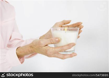 Cropped image of senior businesswoman holding lit candle in office