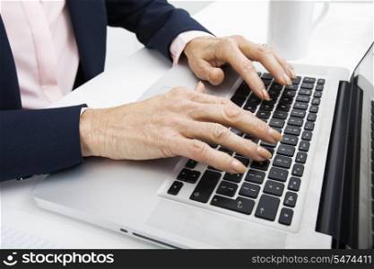 Cropped image of senior businesswoman typing on laptop