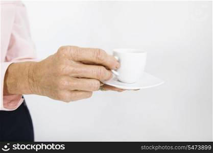 Cropped image of senior businesswoman with espresso cup at office