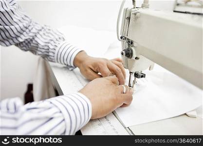 cropped image of tailor sewing cloth on sewing machine