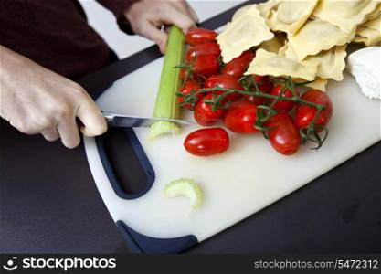 Cropped image of woman chopping cucumber at kitchen counter