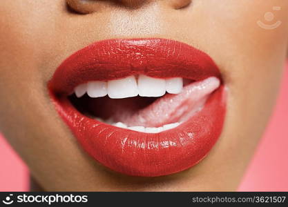 Cropped image of woman licking red lipstick