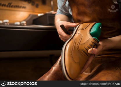 Cropped image of young shoemaker in workshop making shoes.. Shoemaker in workshop making shoes.