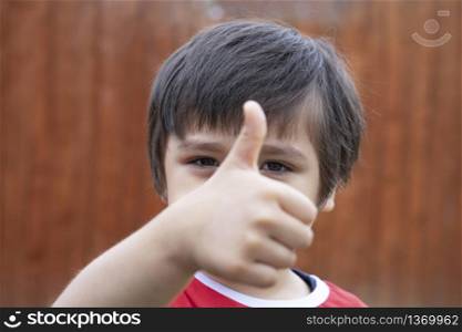 Cropped of school kid giving thumb up as sign of success, Selective focus Child showing his finger, Litle boy relaxing ootside in sunny day spring or summer, Positive children concept
