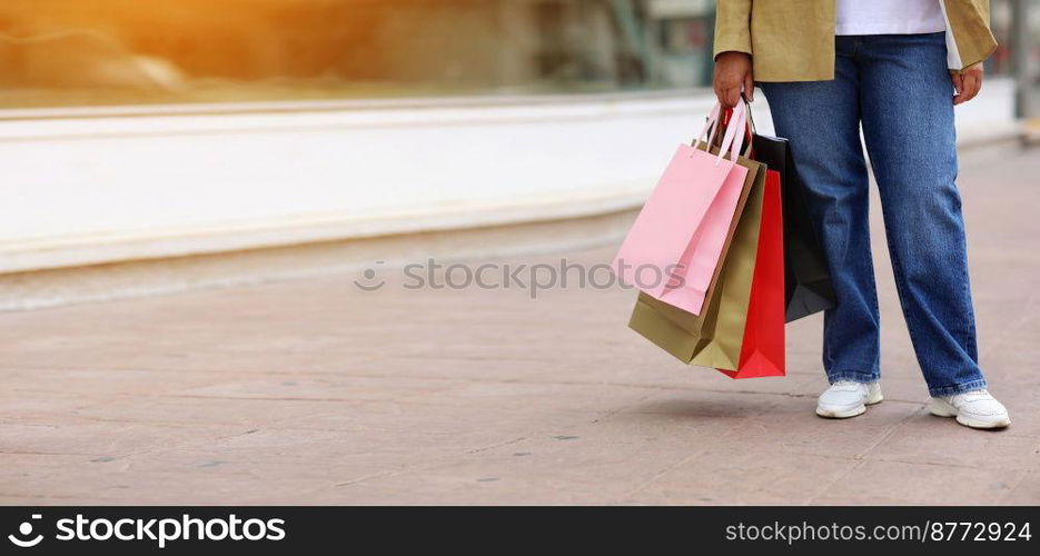 Cropped of unrecognisable woman with colourful shopping bags on urban shopping mall background. Purchases, black friday, discounts, sale concept. Online shopping concept, Seasonal Sales. copy space.. Cropped of unrecognisable woman with colourful shopping bags on urban shopping mall background. Purchases, black friday, discounts, sale concept. Online shopping concept, Seasonal Sales. copy space