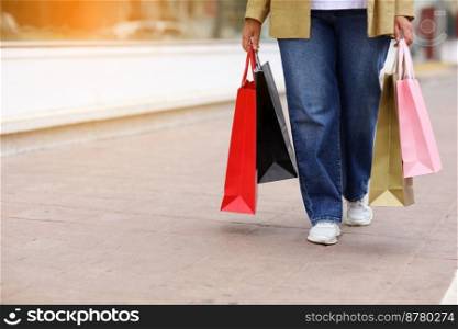 Cropped of unrecognisable woman with colourful shopping bags on urban shopping mall background. Purchases, black friday, discounts, sale concept. Online shopping concept, Seasonal Sales. copy space.. Cropped of unrecognisable woman with colourful shopping bags on urban shopping mall background. Purchases, black friday, discounts, sale concept. Online shopping concept, Seasonal Sales. copy space