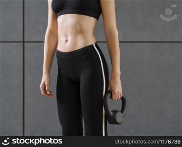 Cropped photo of a young woman in her twenties holding a kettlebell.