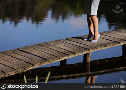 cropped photo of female legs walking on a wooden pier on the river.. cropped photo of female legs walking on a wooden pier on the river