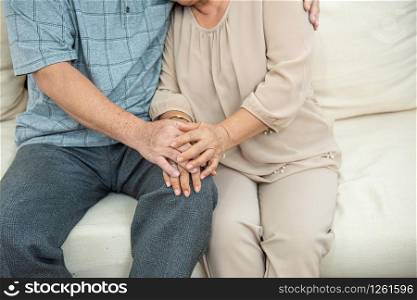 Cropped photo of hands of cute elder senior asian couple holding hands with love on sofa.Old people hug and holding hands. couple concept. loving concept. caring concept.