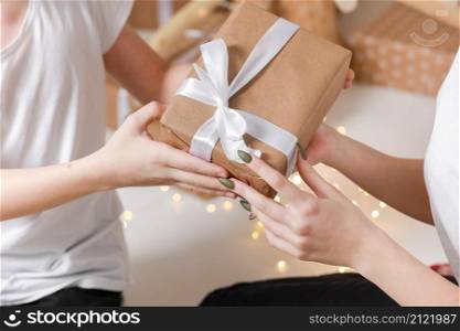 Cropped photo of Young man giving a gift box to his surprised happy woman. party moment. Hands of young boyfriend surprise in box with white ribbon to his girlfriend. Cropped photo of Young man giving a gift box to his surprised happy woman. party moment. Hands of young boyfriend surprise in box with white ribbon to his girlfriend.