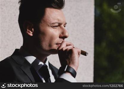 Cropped portrait of hard gaze businessman while smoking a cuban cigar. Cropped portrait of hard gaze businessman while smoking a cuban cigar.