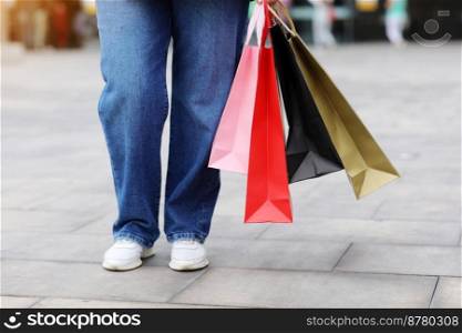 Cropped portrait of unrecognisable woman with colourful shopping bags on urban shopping mall background. Purchases, black friday, discounts, sale concept. Online shopping concept, Seasonal Sales. Cropped portrait of unrecognisable woman with colourful shopping bags on urban shopping mall background. Purchases, black friday, discounts, sale concept. Online shopping concept, Seasonal Sales.