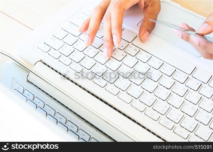 Cropped shot of a young woman using notebook computer and credit card, woman's hands using laptop computer for online shopping. Shopping online concept or using technology.
