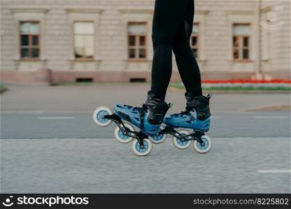 Cropped shot of faceless woman wears rollerblades for riding on road enjoys hobby in fresh air has active lifestyle tries new rollers after purchasing. People hobby and outdoor free time activities