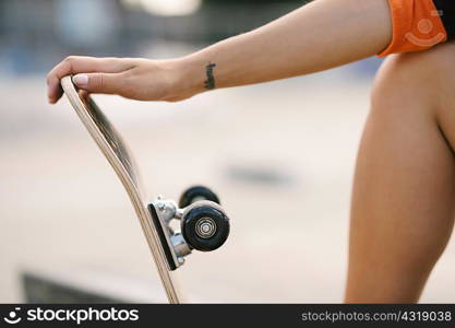 Cropped shot of female skateboarder holding skateboard
