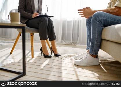 Cropped shot of psychologist and patient leg. Female doctor and man conversation on therapy session. Psychologist and patient talking during therapy session