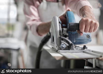 Cropped shot of senior carpenter using machine in wood workshop