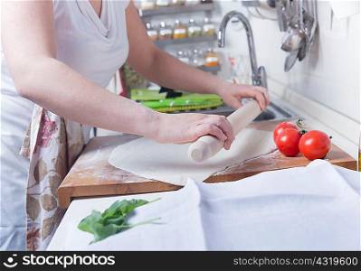 Cropped shot of woman rolling out pastry on kitchen counter
