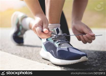 Cropped shot of young women runner tightening running shoe laces