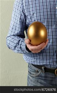 Cropped Studio Shot Of Man Holding Golden Egg