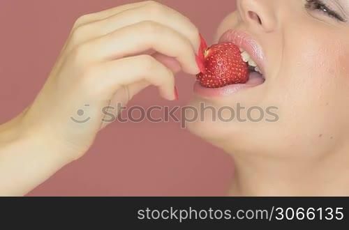 Cropped view portrait of the face of a beautiful sexy woman with smiling eyes eating a strawberry