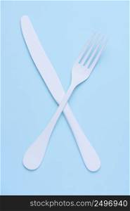 Croseed knife and fork symbol concept on trendy pastel blue background