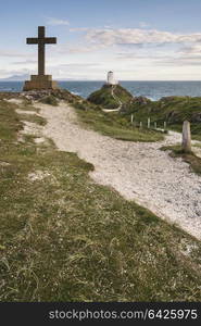 Cross in landscape of Ynys Llanddwyn Island with Twr Mawr lighthouse in background