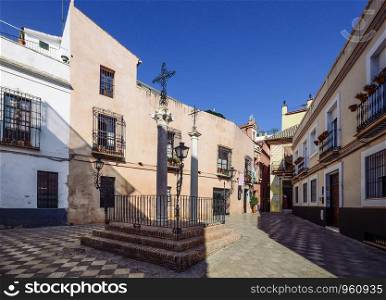 Cross of Locksmith in the famous neighborhood of Holy Cross, also known as Barrio de Santa Cruz, Seville, Andalusia, Spain, a former Jewish Quarter - wide angle view. Santa Cruz District in Seville, Andalusia, Spain