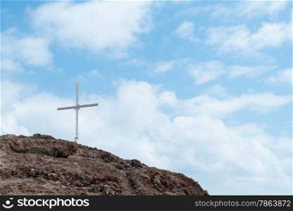 Cross on Rugged Summit with Blue Sky and Fluffy White Clouds